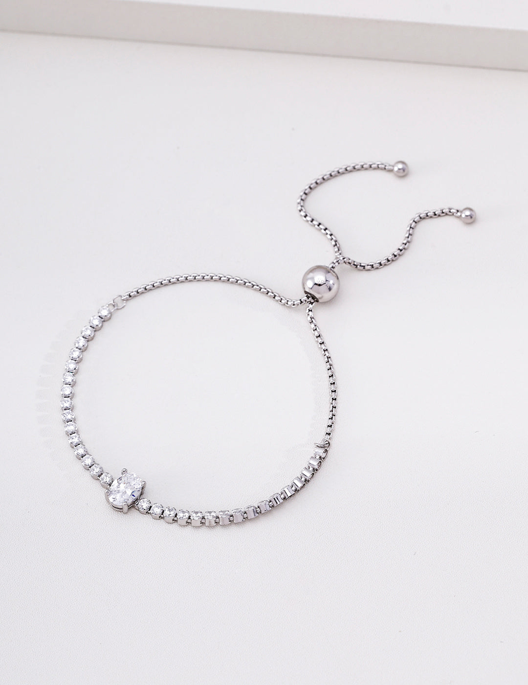 Silver cubic zirconia tennis bracelet with an oval centre stone and adjustable sliding clasp
