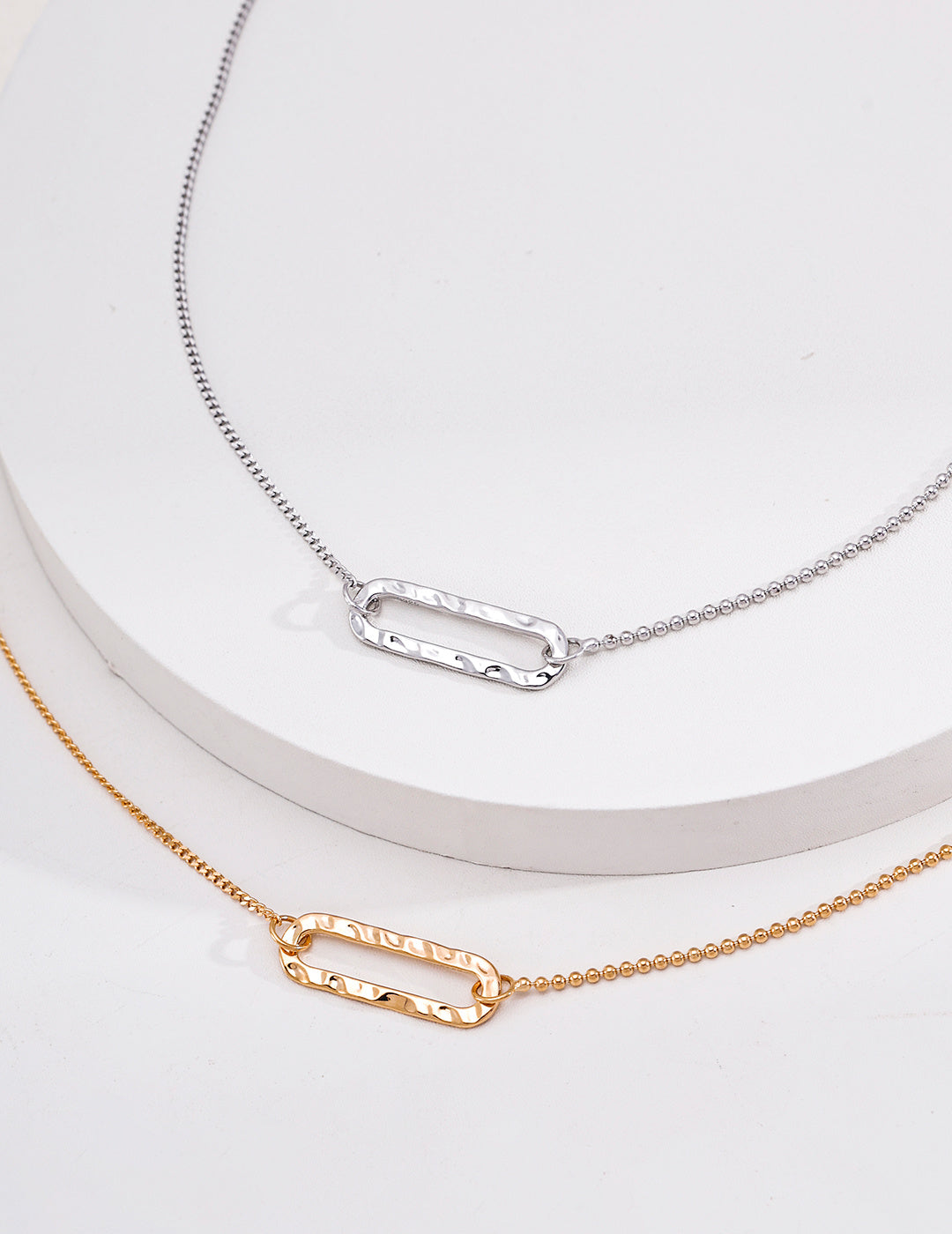 Vintage gold and silver open rectangle pendant necklaces displayed on white blocks