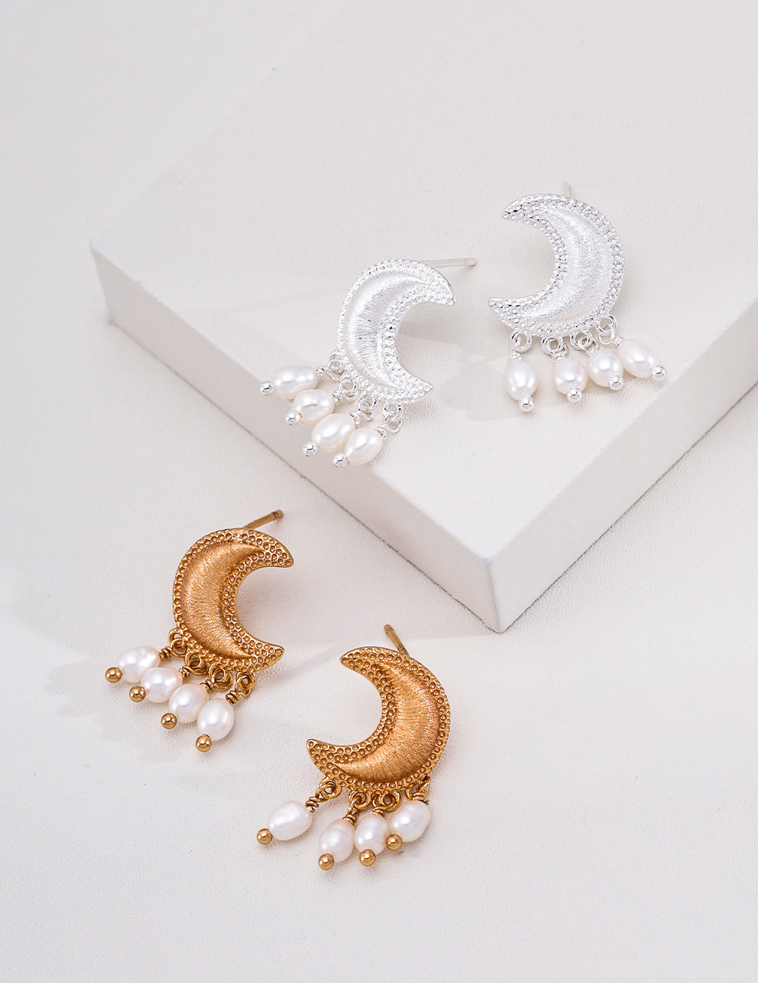 Vintage gold and silver crescent moon earrings with natural pearl drops displayed on white blocks