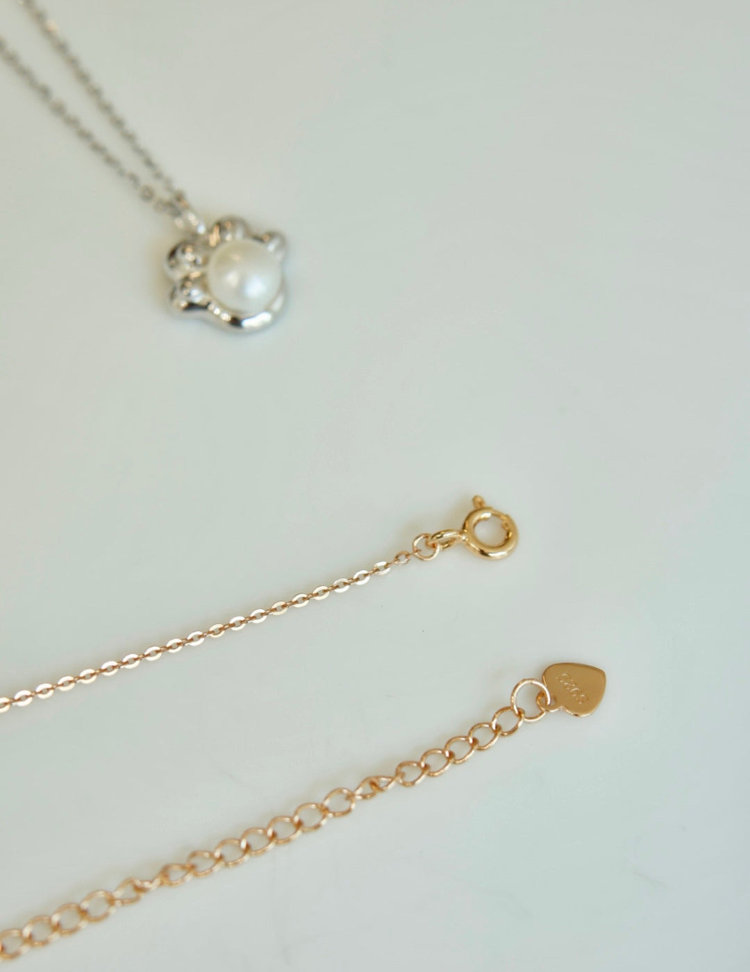Gold necklace with a heart-shaped clasp on a light background
