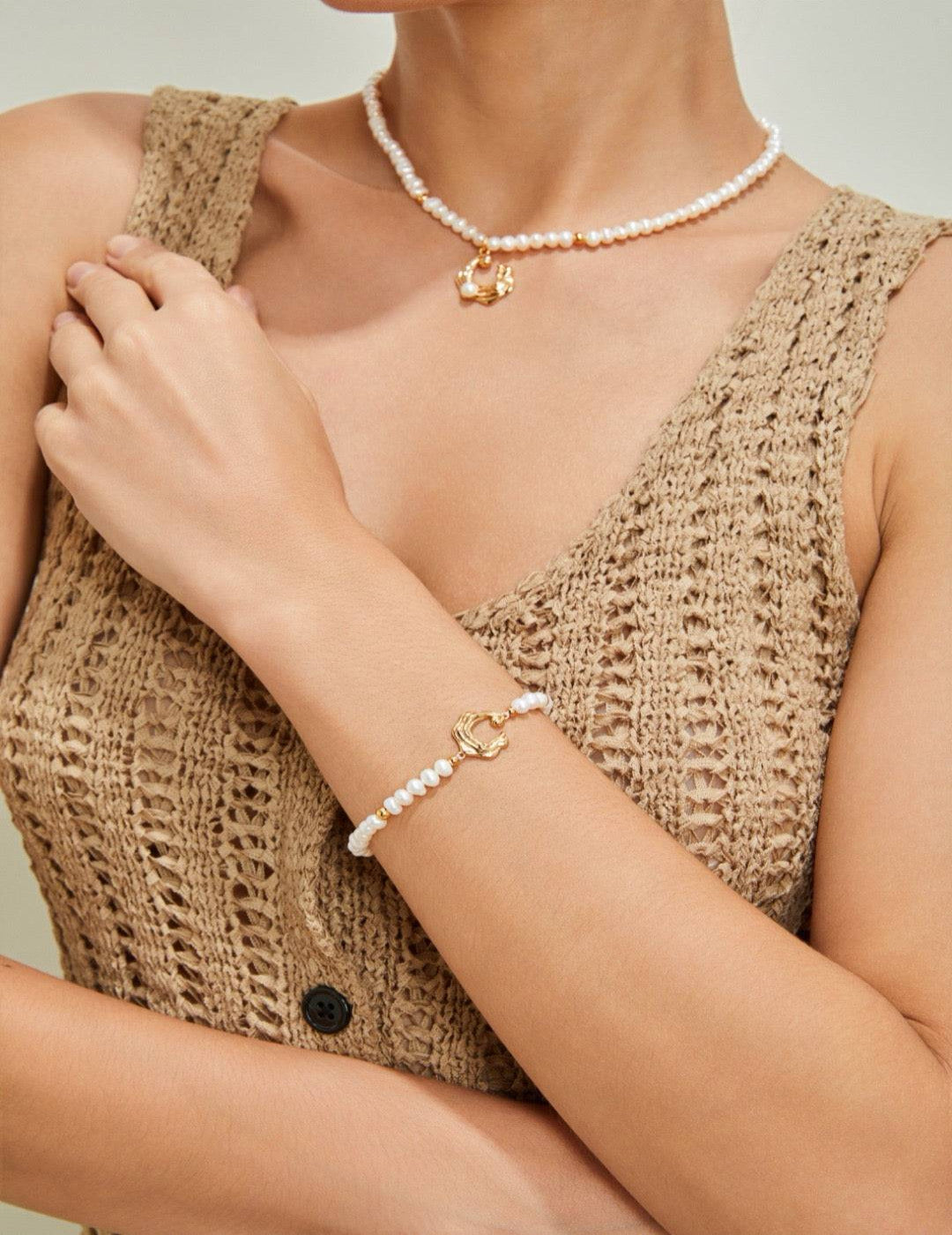 Model wearing gold wave clasp pearl bracelet