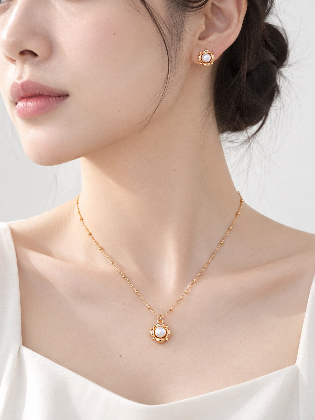 Model wearing vintage gold pearl flower stud earrings and a matching pearl pendant necklace