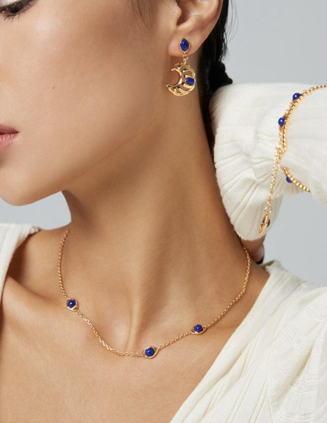 Woman wearing a delicate blue gemstone necklace at collarbone length