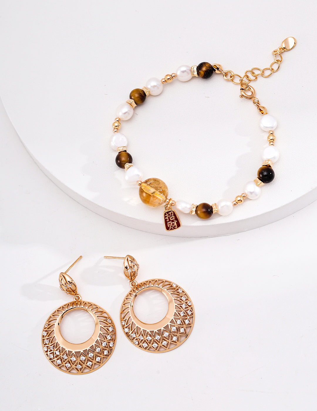 Vintage gold filigree circle drop earrings styled beside a pearl and brown beaded bracelet