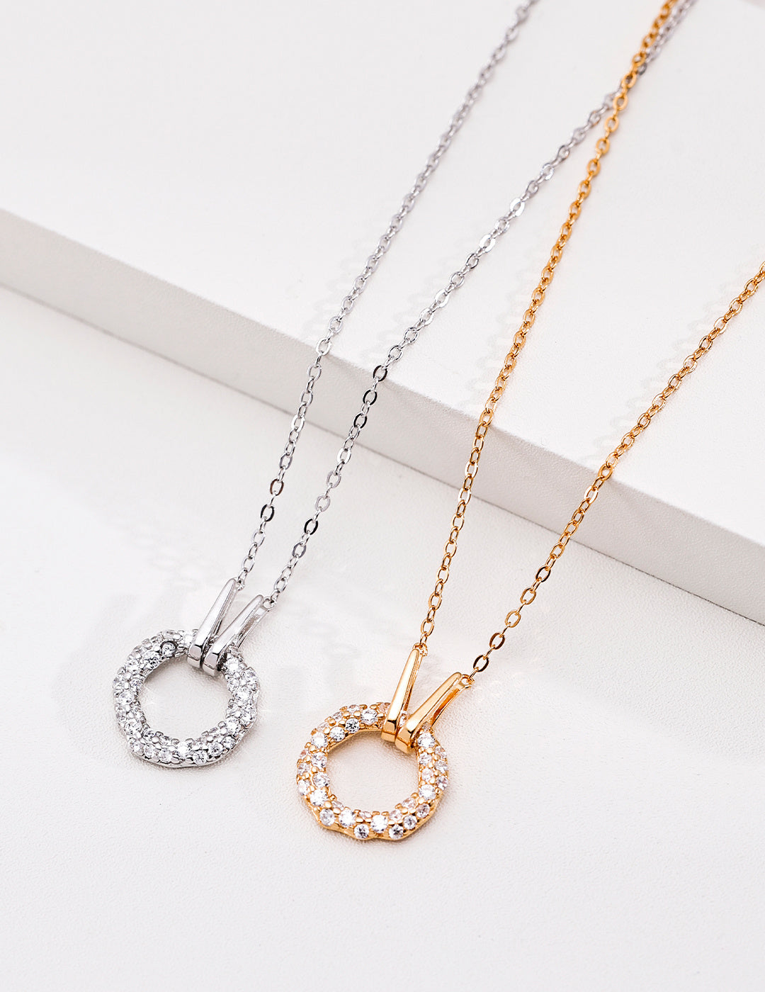 Vintage gold and silver cubic zirconia circle pendant necklaces displayed together on a white block