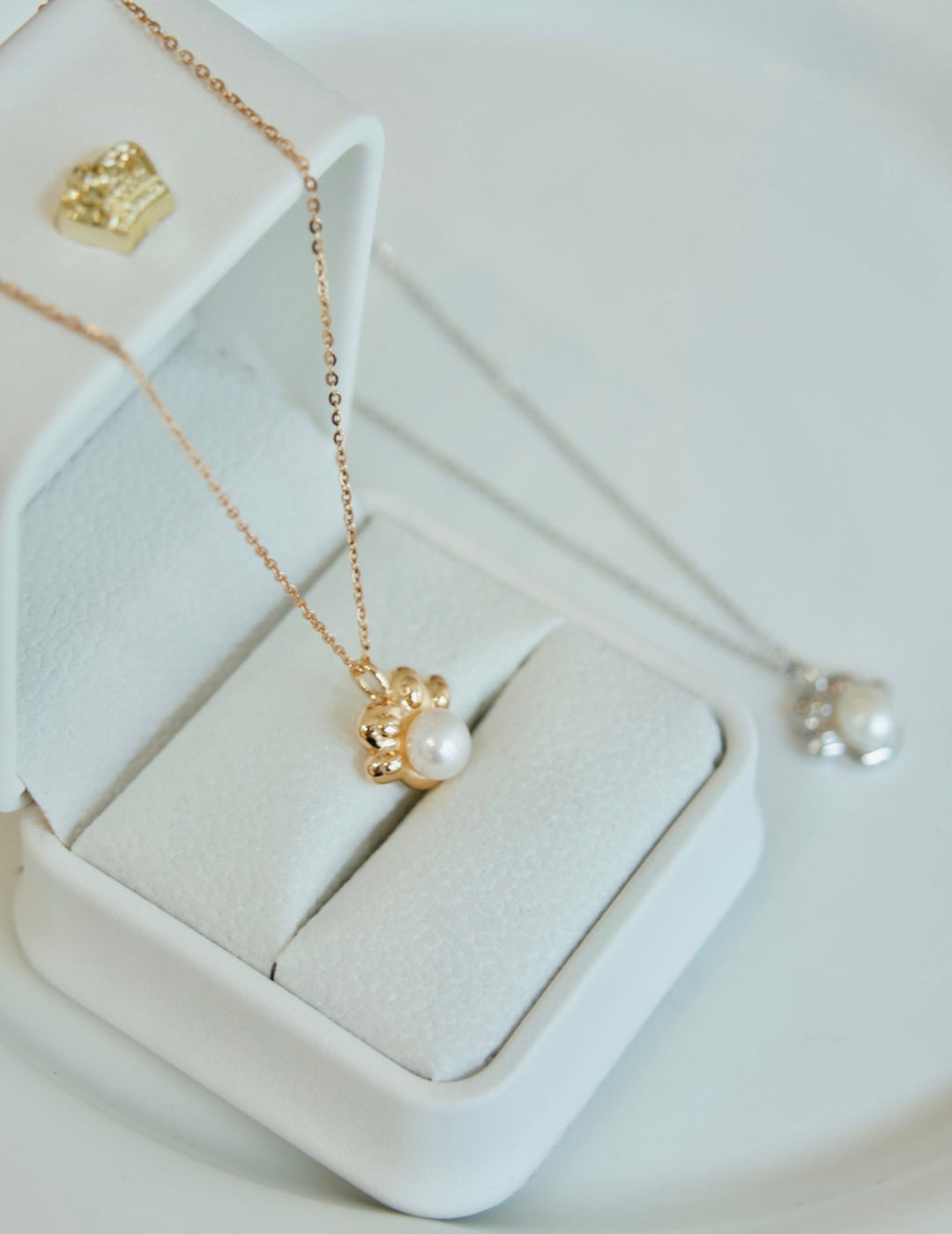Gold necklace with a pearl pendant on a white jewelry box
