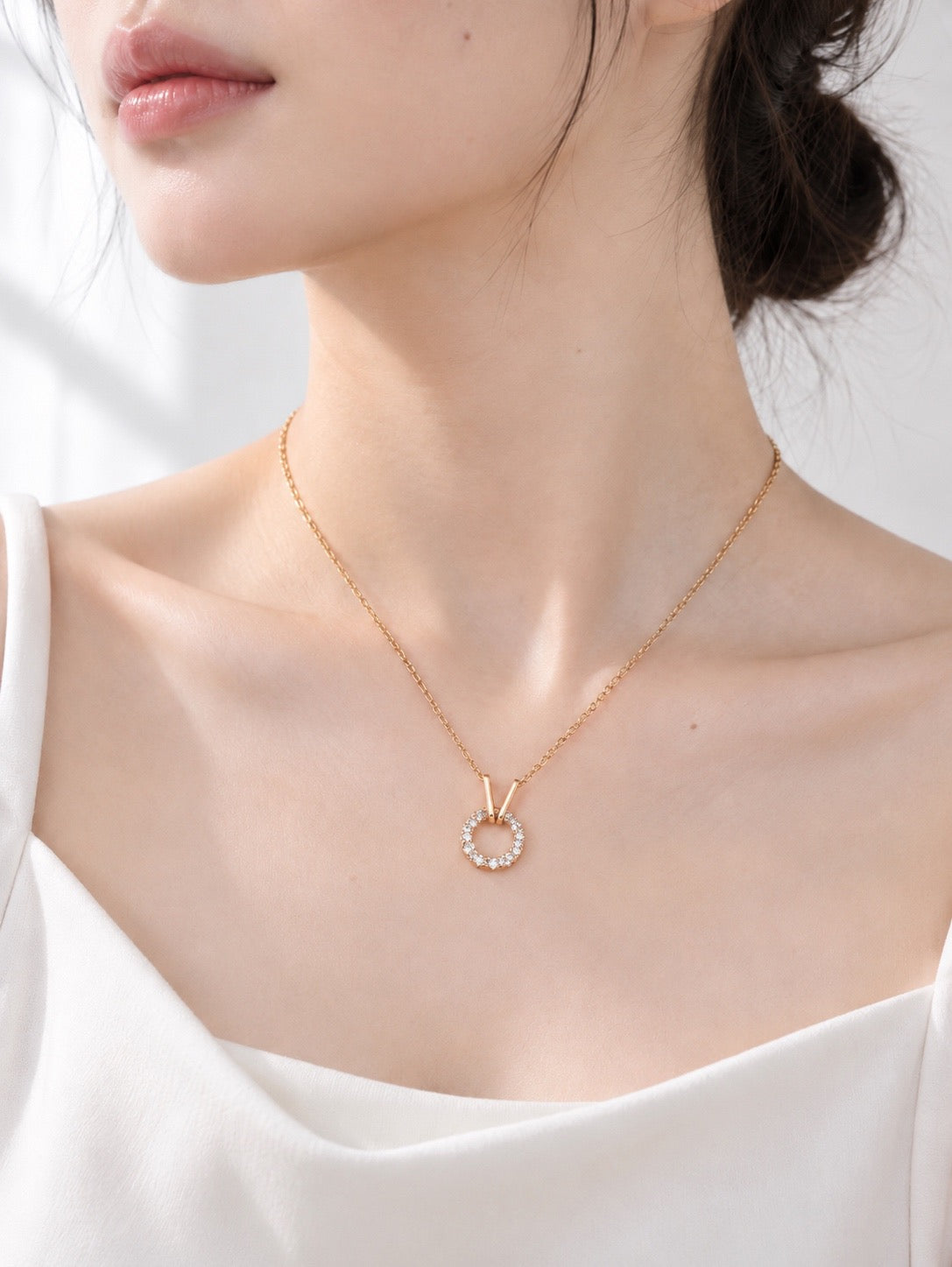 Model wearing a vintage gold cubic zirconia circle pendant necklace with a white top